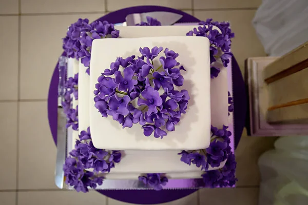 Three-tiered white cake with purple flowers