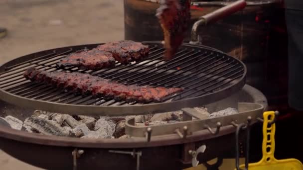 Un hombre prepara costillas de cerdo en la parrilla — Vídeo de stock