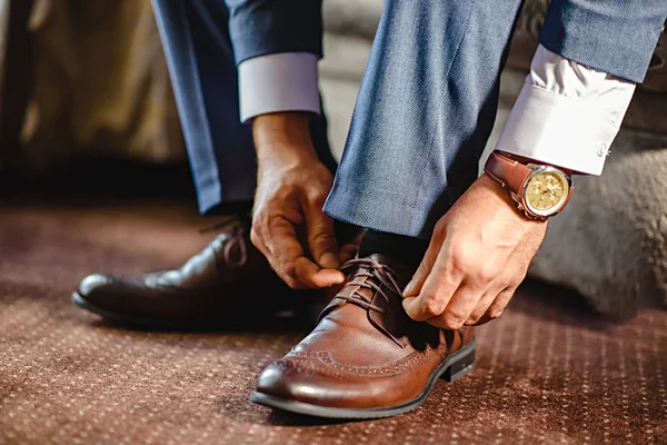 Ein eleganter Mann zieht schwarze, lederne, formelle Schuhe an. — Stockfoto