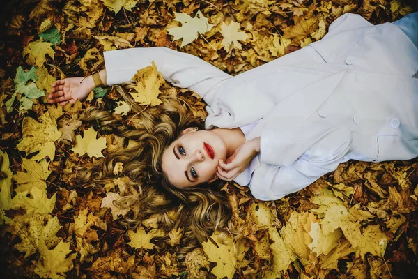 若い女性は黄色の葉に横たわっています,笑顔幸せな女性の肖像画,上からの眺め — ストック写真