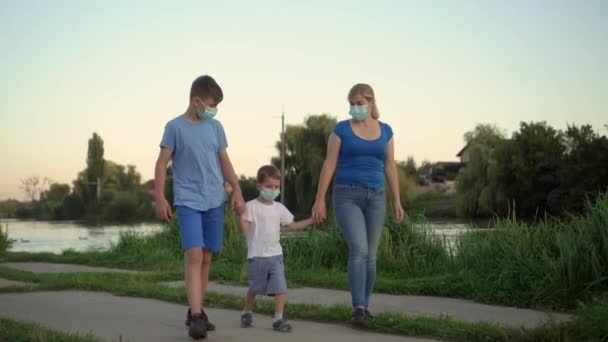 Een familie met een kind met medische maskers lopen in de buurt van het meer — Stockvideo