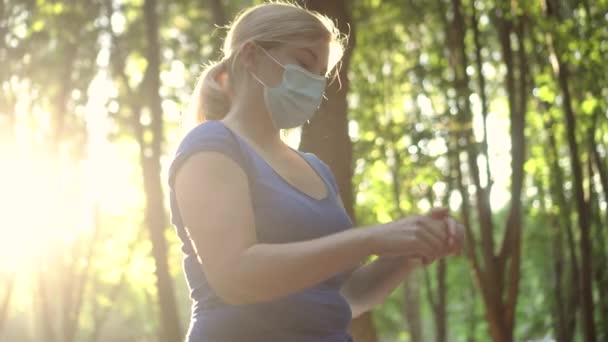 Een vrouw met een medisch masker behandelt haar handen met ontsmettingsmiddel — Stockvideo