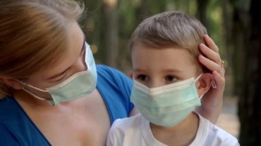 Tıp maskeli anne ve oğlu parkta oturuyor.