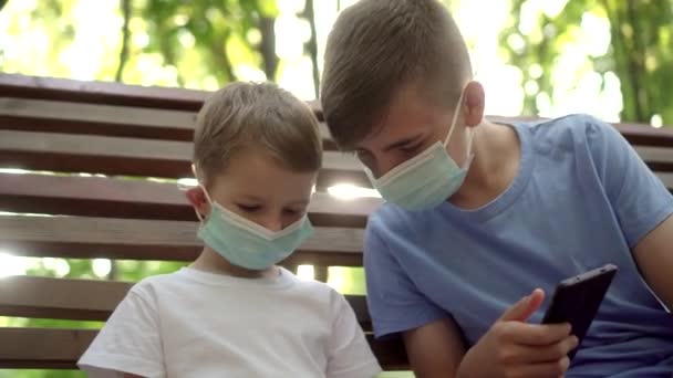 Niños Con Máscaras Médicas Juegan Con Smartphones Park — Vídeos de Stock
