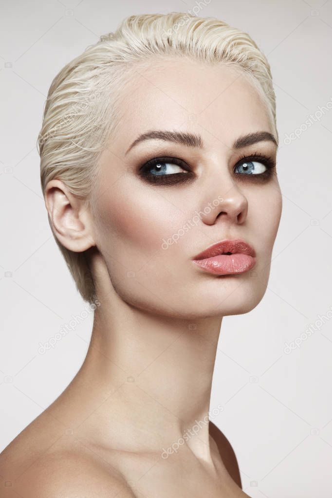 Young beautiful blonde woman with pixie hair cut and smoky eye make-up