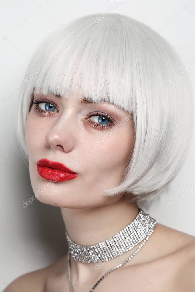 Glamorous portrait of young woman with platinum blonde hair and red lips on white background 