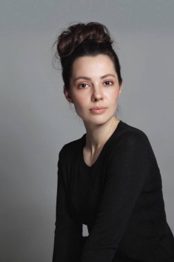 Gri arka plan üzerinde doğal makyaj ve fantezi saç topuz ile genç kadın Portresi