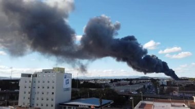 Valencia, İspanya - 21 Ocak 2019: Bir büyük tüy siyah endüstriyel bir yangından duman. Endüstriyel yangınlar her yıl milyarlarca dolar özelliği ve mal zarar.