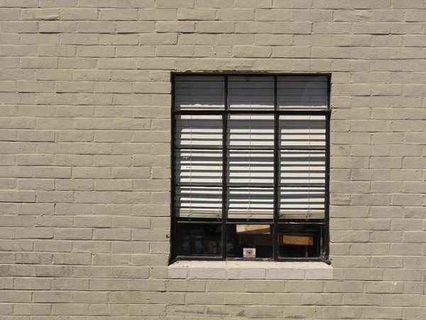 Stare okno z żaluzjami poziomymi w ceglanym budynku zewnętrznym — Zdjęcie stockowe