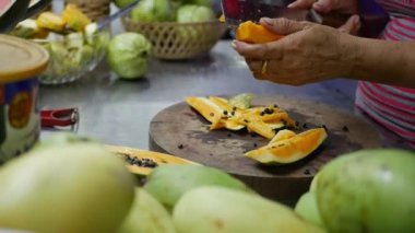 Kadının elleri hazırlamak ve papaya gece Asya pazarında satmak. Egzotik meyveler masanın üzerinde. 4k