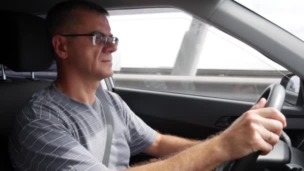 Un hombre mayor conduce un coche en la autopista. Un hombre conduciendo su coche en vacaciones. 4k — Vídeo de stock