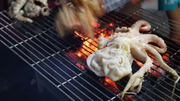 Matlagning på grillning bläckfisk på utomhus asiatiska gatumarknad på natten. Grilla fisk och skaldjur. 4k — Stockvideo