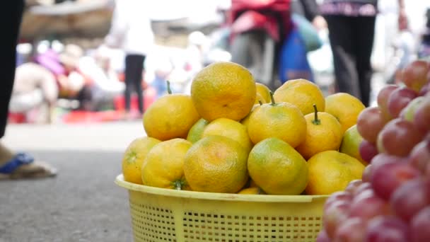 Nahaufnahme einer Menge orangefarbener Mandarinen und Trauben in einem Korb auf dem lokalen vietnamesischen Markt — Stockvideo