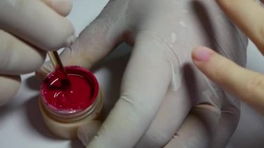 Closeup manikürcü kırmızı bir jel oje karışımları. Güzellik Spa salonunda kadın manikür yapıyor