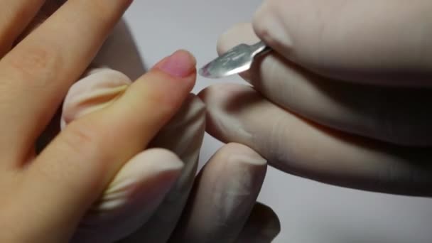 Primer plano maestro de la manicura corrige las uñas esmalte base de cliente femenino. Mujer en salón de spa de belleza haciendo manicura — Vídeo de stock
