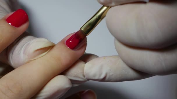 A manicura de close-up aplica um verniz de unha de gel vermelho. Mulher no salão de beleza spa fazendo manicure — Vídeo de Stock