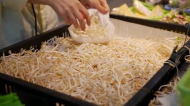Eller bir paket deposunda soya filizi koyar. Genç kadın bir süpermarket bulanıklık arka planda sağlıklı gıda satın