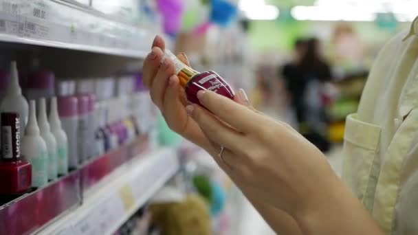 Vrouw zij kiezen en kopen van een nagellak in een schoonheidssalon. Een vrouw met cosmetica — Stockvideo