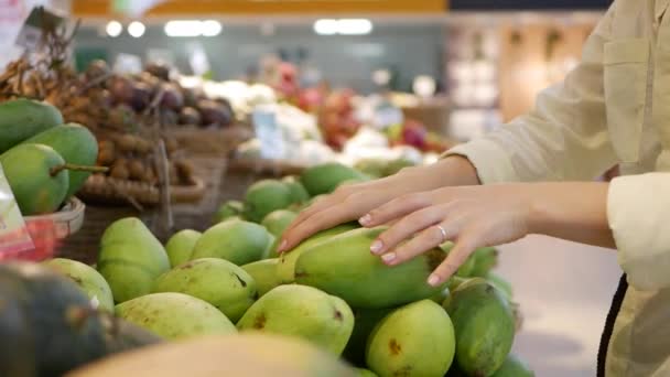 Mujeres manos la elección de los mangos frescos en el supermercado — Vídeos de Stock