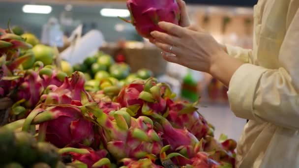 Dames handen kiezen verse rauwe dragon fruit in de supermarkt — Stockvideo