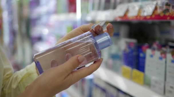 Ženská ruka vybere a koupí tekutý make-up remover. Žena zvolí krém pro péči o obličej a kosmetické přípravky. — Stock video