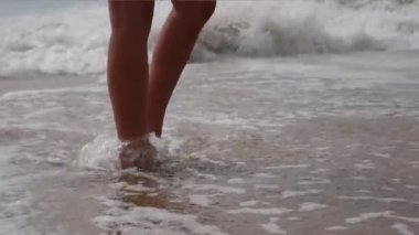 Kadın çıplak ayak yaz sahilde yürüyüş. Deniz suyu ve kum dalga sahilde yürüyen genç kadın bacak kadar kapatın.