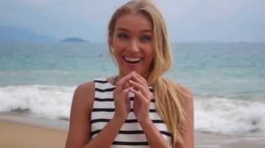 Gülümseyen ve deniz fırtınası bir arka plan karşı ellerini yükselterek neşeli genç güzel kız