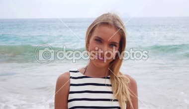 Kamera ve gülümsüyor karşı arka planda denizde fırtına genç çekici seksi kadın bakar. Tropikal bir kumsalda yürüyen güzel neşeli kadın.