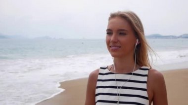 Fırtına vasıl geçmiş üzerinden denizde yürüyüş müzik dinler ve kulaklık ile siyah beyaz elbiseli uzun sarı saçlı genç güzel ince kadın.