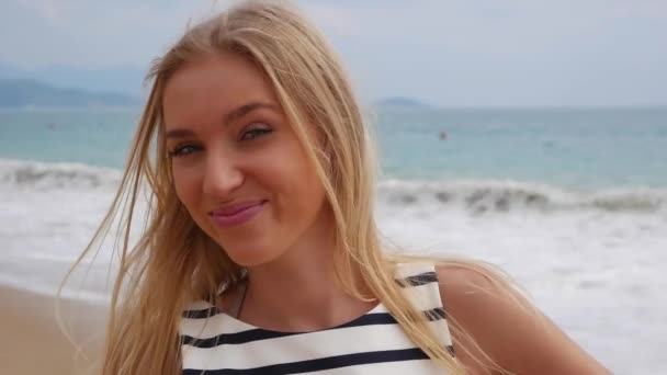 Alegre joven hermosa chica sonriendo guiño mirando a la cámara sobre el fondo en la tormenta en el mar — Vídeo de stock