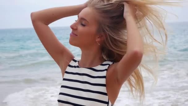 Joven atractiva mujer sexy mira a la cámara y sonríe contra el fondo en una tormenta en el mar. Hermosa mujer alegre caminando en una playa tropical . — Vídeos de Stock