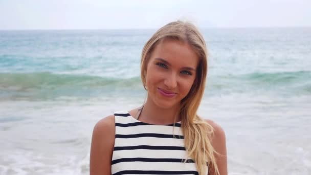 若い魅力的なセクシーな女性は、カメラと背景に海の嵐の笑顔に見えます。熱帯のビーチの上を歩く美しい陽気な女性. — ストック動画