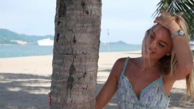 Genç güzel kadın gülümseyen ve mavi deniz arka plan üzerinde avuç içi ağacı yakın hava öpücük gönderme. Romantik konsept. HD, 1920x1080.