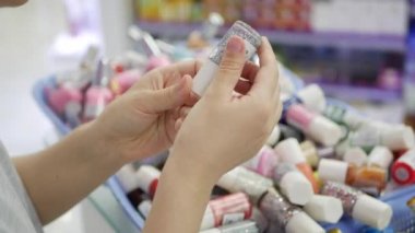 Kadının el seçimi ve oje Güzellik Salonu içinde satın alma. Kozmetik tutan bir kadın