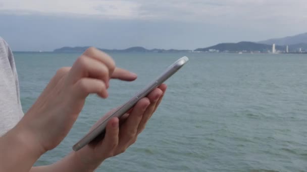 Womans hands using smartphone over background sea and islands. Girl touching screen — Stock Video