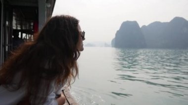 Genç kadın beyaz bir ceket ve güneş gözlüğü gemide otururken körfezin güzel manzaraya arıyoruz. Seyahat kavramı