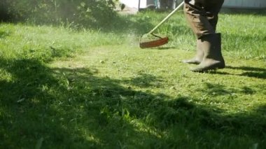 Güneşli bir yaz gününde motor kesme çim ile Benzinli çim biçme makinesi düzeltici ile erkek işçisi. Ülkede çim kesme. Slowmotion