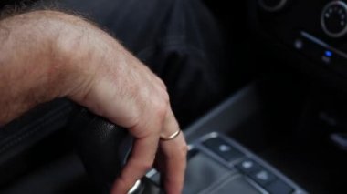 Erkek el vites kutusunu tutuyor. Sürücü arabadaki manüel şanzımanı değiştirir. Adam otomobille gidiyor. Yakın çekim.
