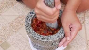 Tay biber ve sarımsak pestle taş harç vurma. Kadın Tay çorbası Tom Yam için sos hazırlanıyor. Yakın çekim. 4k