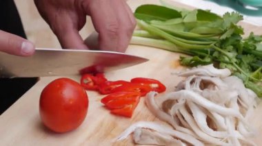 Erkek elleri açık havada mutfakta sebze ve yeşillik kesti. Bir kadın bıçak kullanır ve yemek pişirir. Adım adım, çorba tom yam pişirme. Tay mutfağı Yakın çekim. 4k