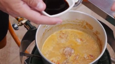 Cook Tay baharatlı çorba kaynayan tencereye soya sosu ekler. Adım adım tom yam çorbası pişirme. Tay mutfağı. Closeup. 4k
