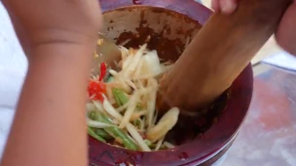 Mulheres tailandesas preparando salada de mamão verde som tam em argamassa de madeira com pilão. Fecha. 4k — Vídeo de Stock