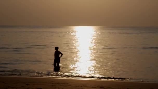 Θολές σιλουέτες ανθρώπων που περπατούν στην παραλία και κολυμπούν στη θάλασσα το ηλιοβασίλεμα. Ιδέα για διακοπές. Closeup. 4K — Αρχείο Βίντεο
