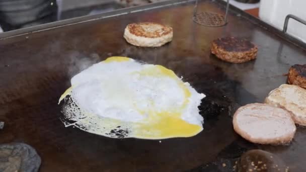 Lager en cheeseburger med egg. Storfekjøtt eller svinekjøtt, fyldig, deilig grillkjøtt på panna. Lukk opp. 4k – stockvideo