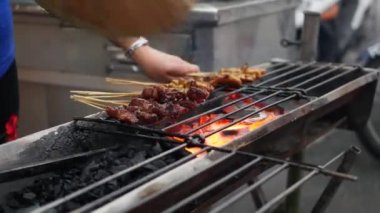 Sokak yerel pazarda pişirilen çubuklar üzerinde geleneksel ızgara et. Satay bbq. Closeup. 4k