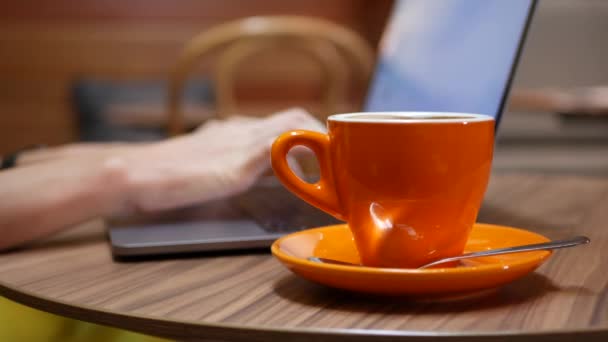 Mujer trabajando en un portátil con una taza de café en la mesa, trabajo distante de un café. Concepto de trabajo independiente. 4k — Vídeos de Stock