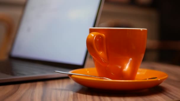 Mujer trabajando en un portátil con una taza de café en la mesa, trabajo distante de un café. Concepto de trabajo independiente. 4k — Vídeo de stock