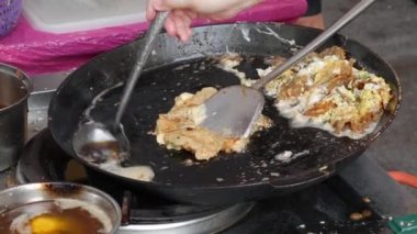 Tay insanlar yumurta ve gevrek un veya istiridye omlet ile kızarmış midye yemek. Gıda festivalinde pazarda insanlara Satılık. Sokak yemeği. Gece pazarı. Closeup. 4k