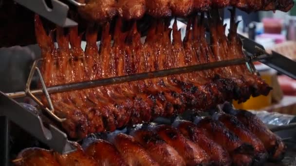 Muchas parrillas de pollo cocidas cuelgan de brochetas de metal en la cocina. Cocina asiática, tailandesa, japonesa, oriental. Primer plano de una parrilla. Comida callejera. Deliciosa carne frita de aves de corral. — Vídeos de Stock