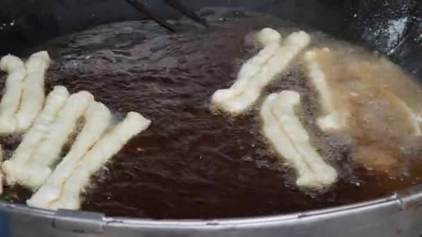 Cook prepare Youtiao, also known as Chinese fried churros, Chinese cruller, Chinese oil stick, Chinese doughnut, You Char Kway, Cakwe, Cakoi, Kueh, Kuay and fried breadstick. Street food concept — Stock Video